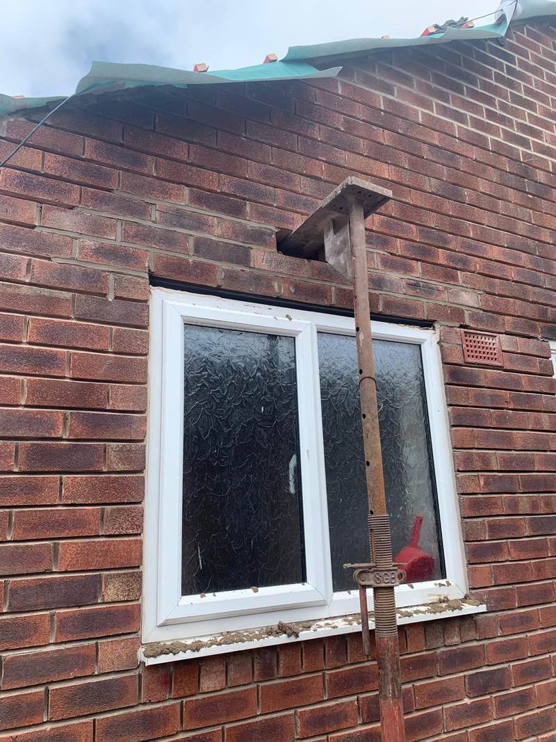 Brickwork repairs around a window with a temporary support in Bolton