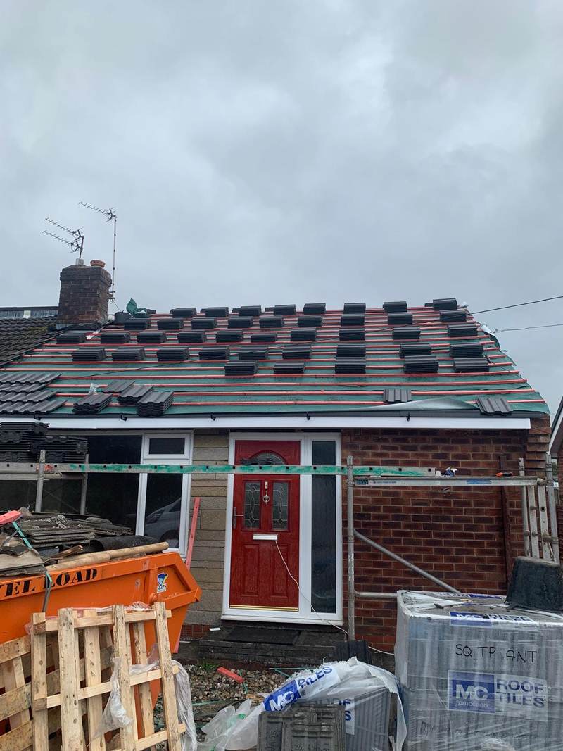New concrete roof tiles being laid on a bungalow re-roof in Bolton