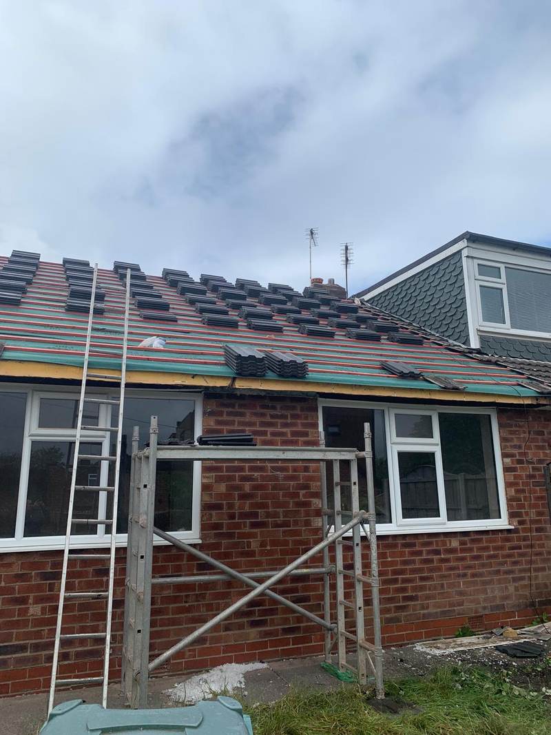 Bungalow rear roof re-tiling in progress with scaffold tower, Bolton